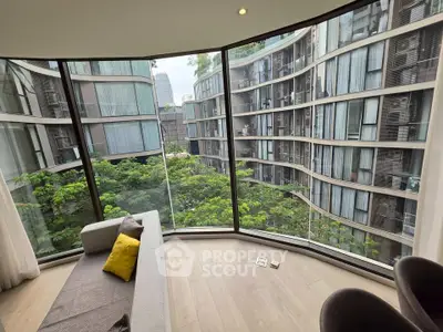 Luxurious apartment with floor-to-ceiling windows offering stunning views of modern architecture and lush greenery.