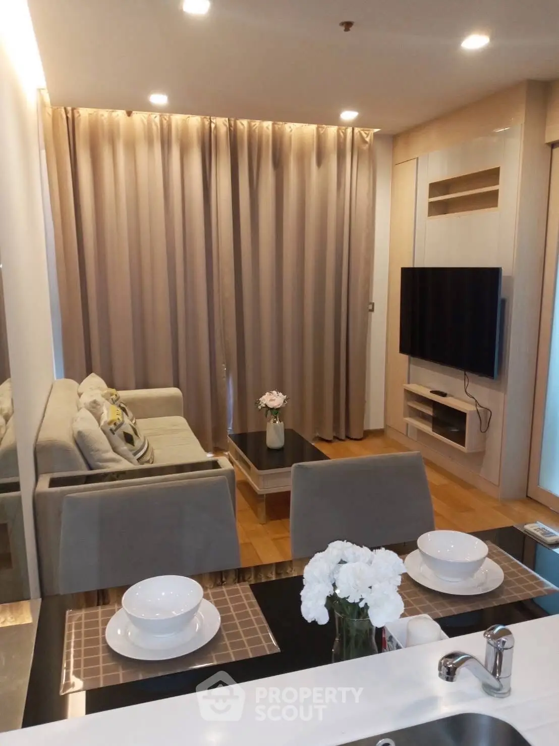Modern living room with elegant decor and open layout, featuring a cozy sofa and wall-mounted TV.