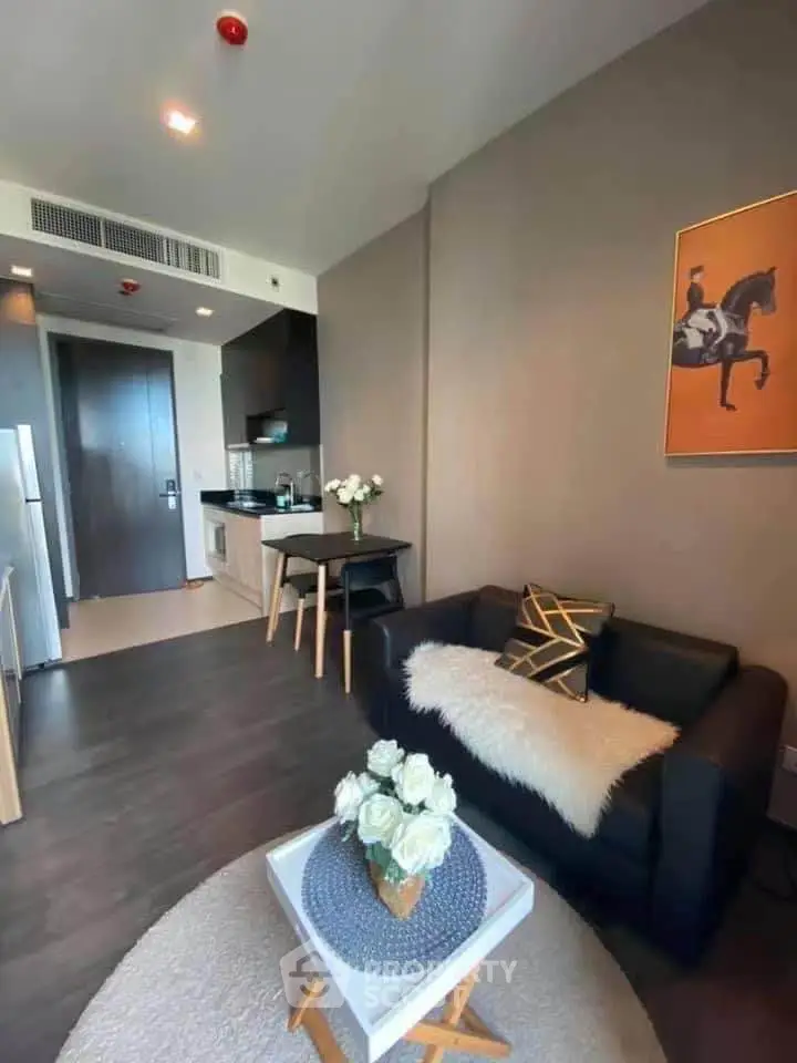 Modern living room with stylish decor and compact kitchen in open layout apartment.
