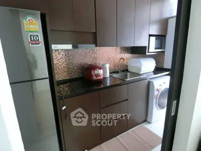 Modern kitchen with sleek cabinets, mosaic backsplash, and appliances including fridge and washing machine.