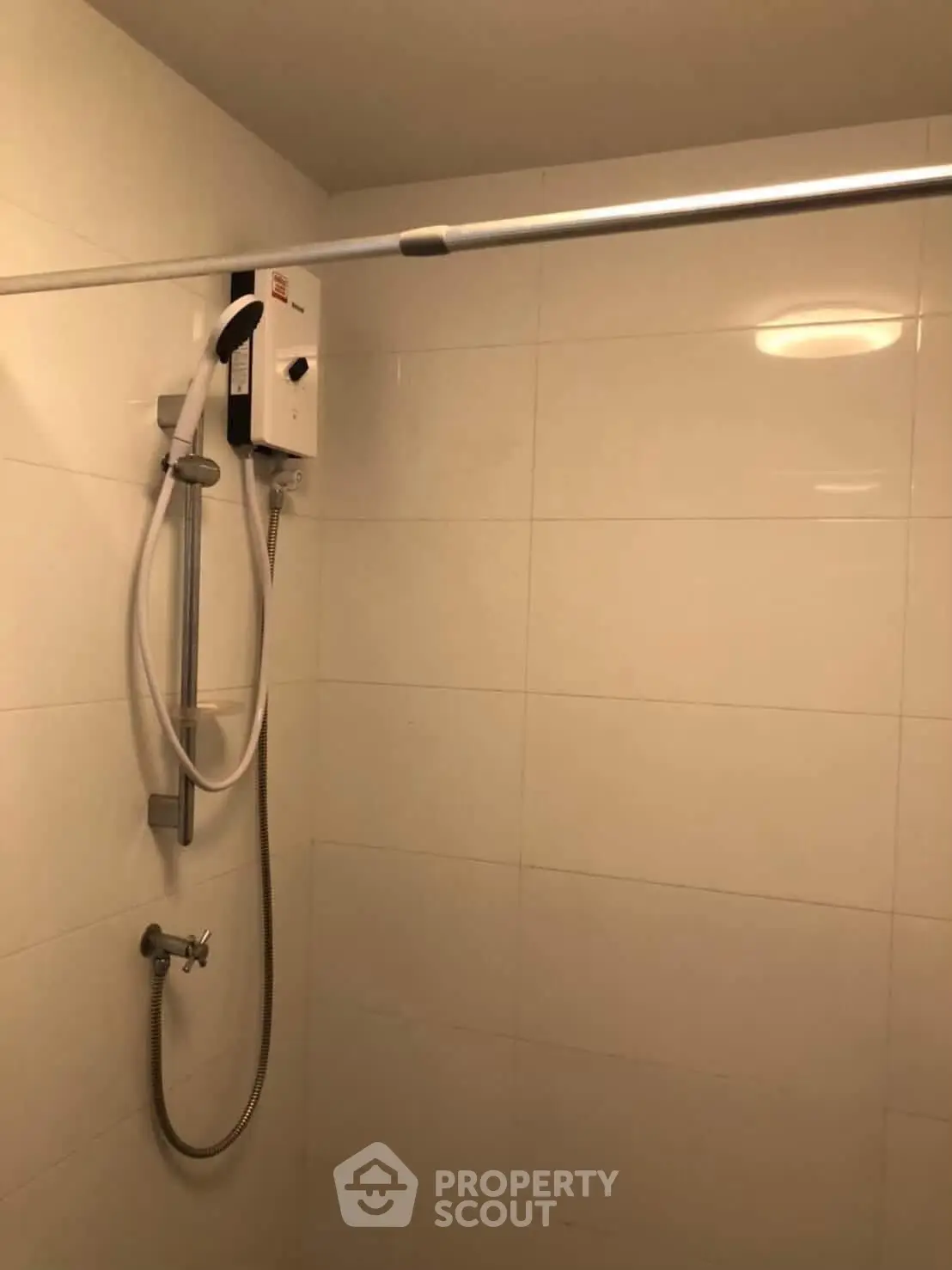 Modern bathroom with sleek shower setup and tiled walls, perfect for a contemporary home.