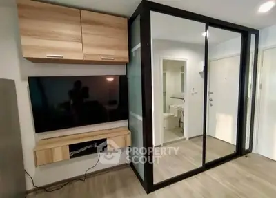 Modern living room with sleek TV setup and mirrored closet doors.