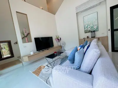 Modern living room with stylish decor and large TV, featuring a cozy sofa and elegant artwork.