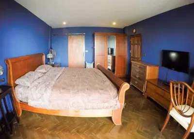 Spacious bedroom with elegant wooden furniture and blue walls, perfect for relaxation.