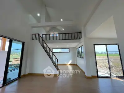Spacious modern living room with high ceilings and large windows offering natural light and scenic views.