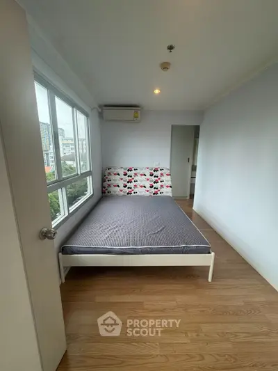 Cozy bedroom with large window and wooden flooring in modern apartment