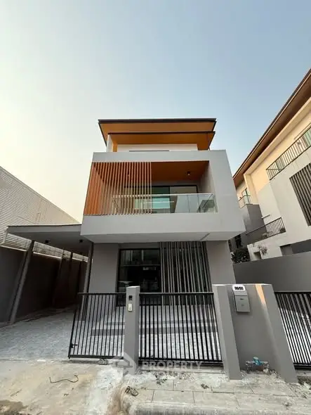 Modern three-story house with sleek design and spacious balcony in a contemporary neighborhood.