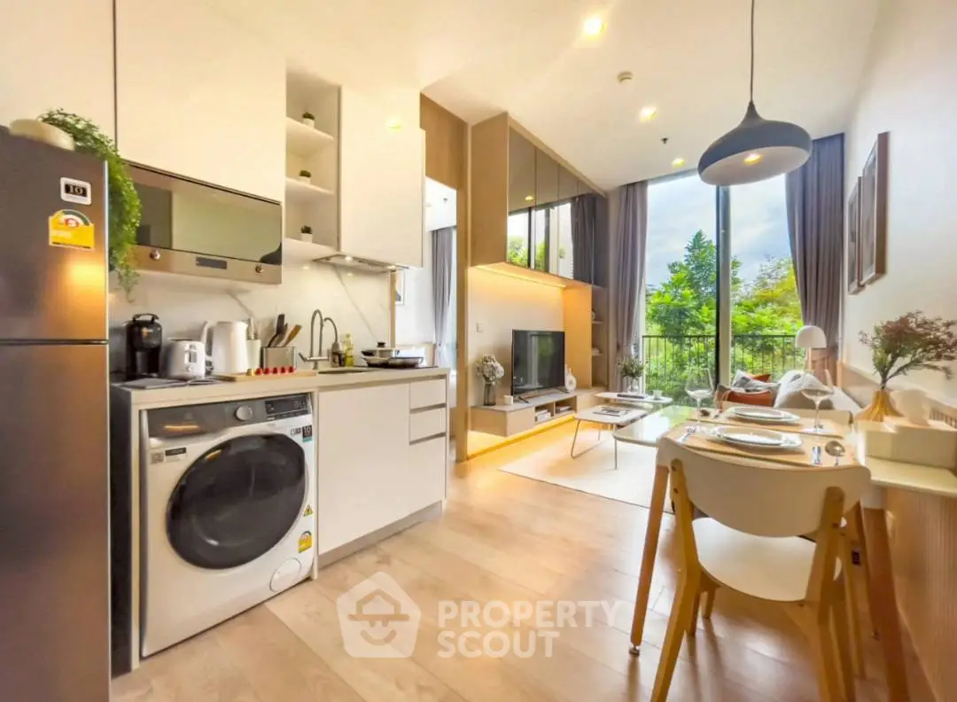 Modern open-plan living room with kitchen, featuring large windows and stylish decor.