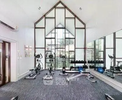 Spacious modern gym with large windows and fitness equipment in a stylish building.