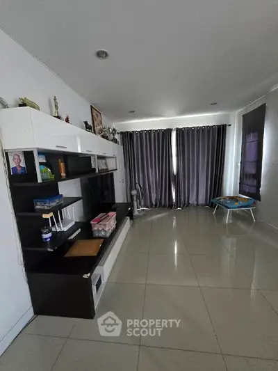 Spacious living room with modern entertainment unit and large windows.