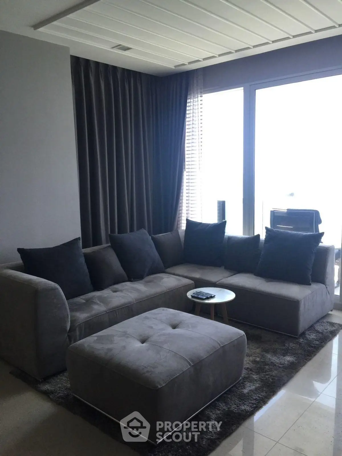 Modern living room with sleek gray sectional sofa and floor-to-ceiling windows