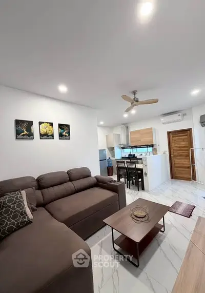 Modern living room with open kitchen, stylish decor, and cozy seating area in a contemporary apartment.
