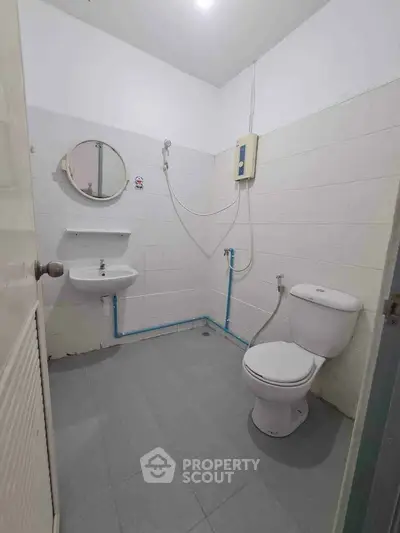 Compact bathroom with shower, sink, and toilet in minimalist design.