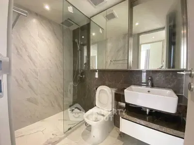 Modern bathroom with glass shower and sleek fixtures in luxury apartment.