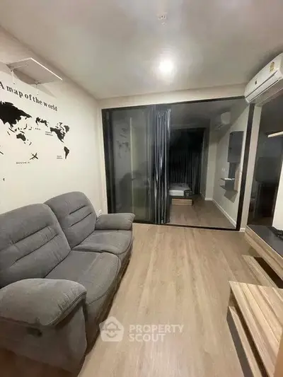 Modern living room with cozy sofa and world map wall art, featuring sleek wooden flooring and air conditioning.