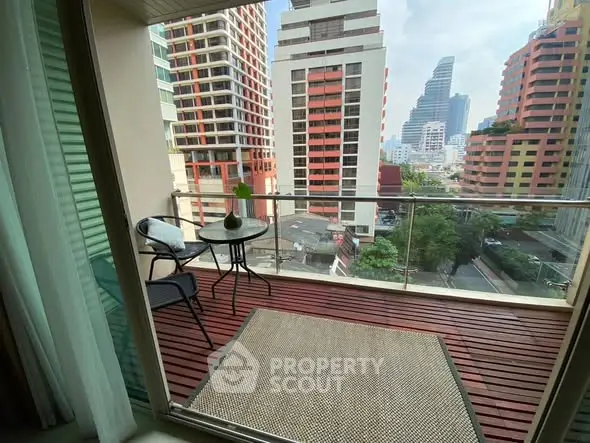 Charming city view from a cozy balcony with modern furniture and glass railing.