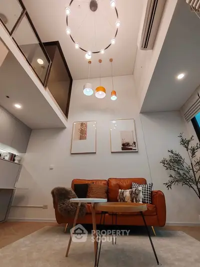 Modern living room with high ceiling, stylish lighting, and cozy seating area in a contemporary apartment.