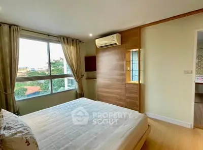 Spacious bedroom with large window and modern air conditioning unit, offering a comfortable and bright living space.