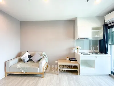 Modern living room with cozy sofa and sleek kitchenette in open layout apartment.