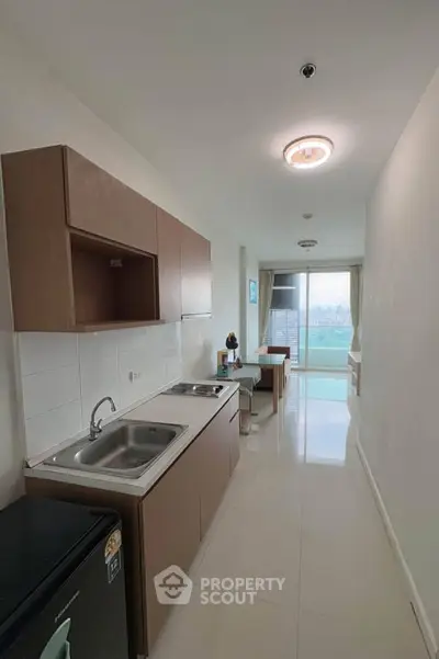 Modern kitchen with sleek cabinetry and open layout leading to a bright living area with city views.