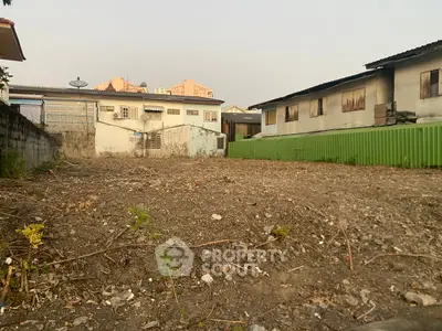 Vacant land plot ready for development in urban area with surrounding buildings.