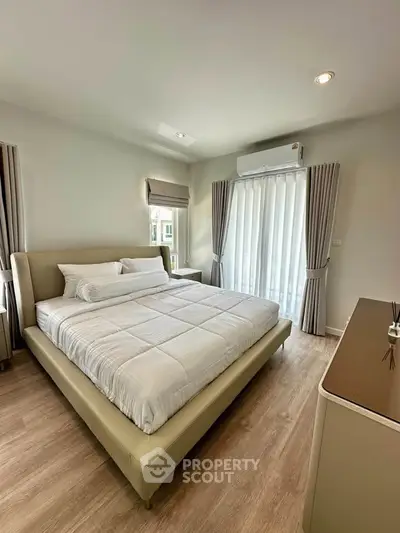 Spacious bedroom with modern decor and natural light, featuring a large bed and elegant curtains.