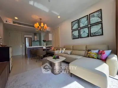 Modern living room with elegant decor and open kitchen layout, featuring a cozy sectional sofa and stylish chandelier.