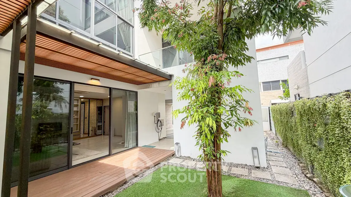 Modern home exterior with lush garden and wooden deck, perfect for relaxation.