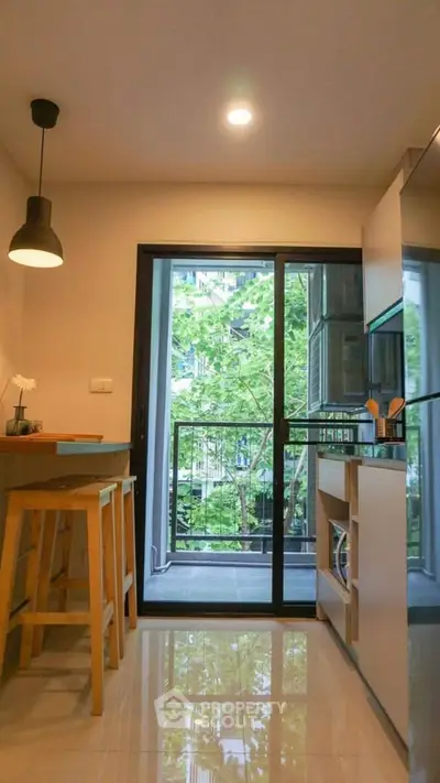 Modern kitchen with open layout and balcony view, featuring sleek cabinetry and stylish lighting.