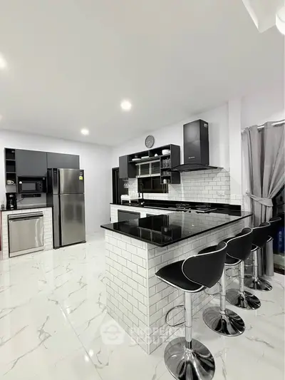 Modern kitchen with sleek black countertops and stylish bar stools in a contemporary home.