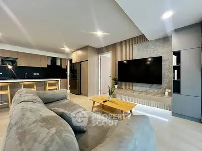 Modern living room with open kitchen, sleek furniture, and large TV for ultimate comfort.