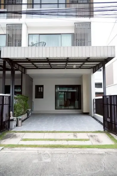 Modern townhouse exterior with covered parking and sleek design.