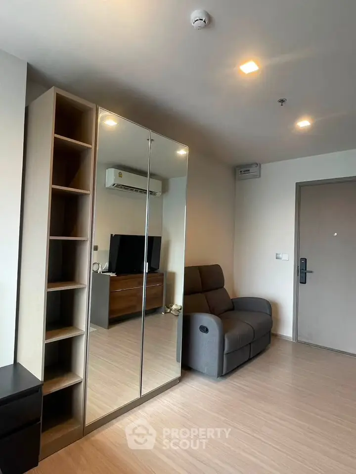 Modern living room with mirrored wardrobe and cozy seating in stylish apartment.