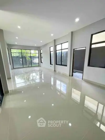 Spacious modern living room with large windows and glossy tiled floors