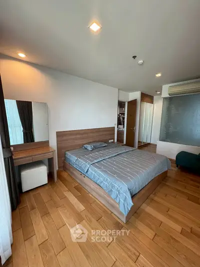Spacious bedroom with wooden flooring and modern furnishings in a stylish apartment.