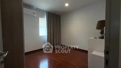 Spacious empty bedroom with wooden flooring and natural light.