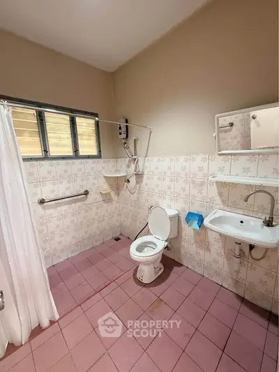 Spacious bathroom with shower and toilet in a tiled setting, ideal for accessibility.