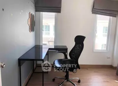 Modern home office with sleek black desk and ergonomic chair, bright natural light from windows