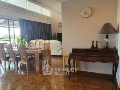 Spacious living room with elegant dining area and parquet flooring, featuring large windows for natural light.