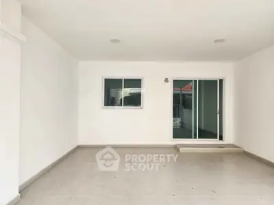 Spacious covered patio with sliding glass doors and tiled flooring, ideal for outdoor relaxation.