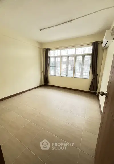 Spacious empty room with large windows and tiled flooring, perfect for customization.