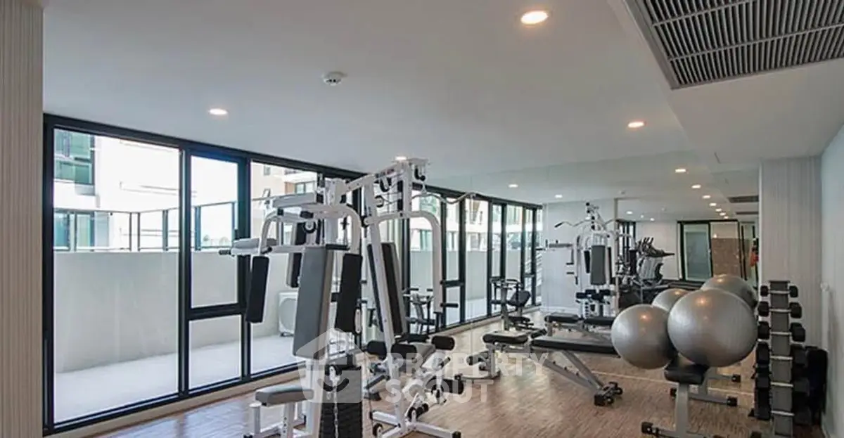 Modern gym with state-of-the-art equipment and large windows in a luxury residential building.