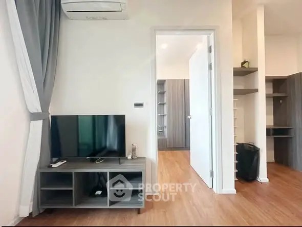 Modern living room with sleek TV stand and air conditioning, featuring stylish wood flooring and open shelving.
