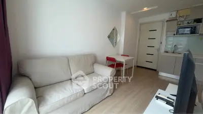 Modern living room with cozy sofa and compact kitchen in open layout apartment.