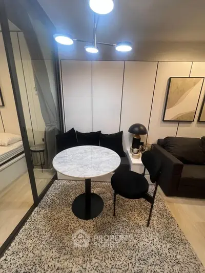 Modern living room with stylish decor, featuring a marble table, black chairs, and contemporary lighting.