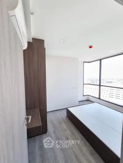 Modern bedroom with large windows and built-in storage in a high-rise apartment
