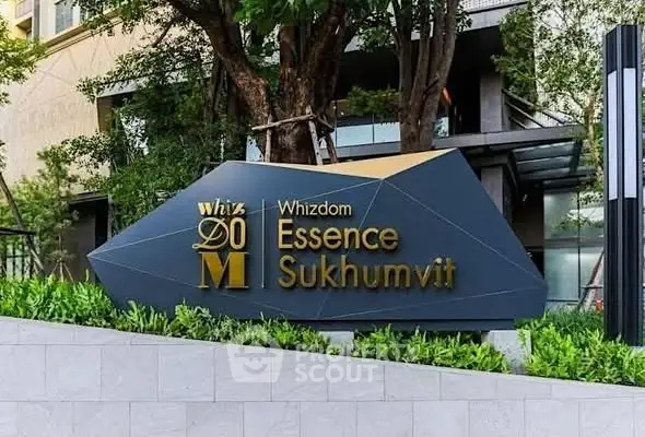 Modern exterior signage of Whizdom Essence Sukhumvit amidst lush greenery.