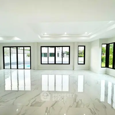 Spacious modern living room with large windows and glossy marble floors.