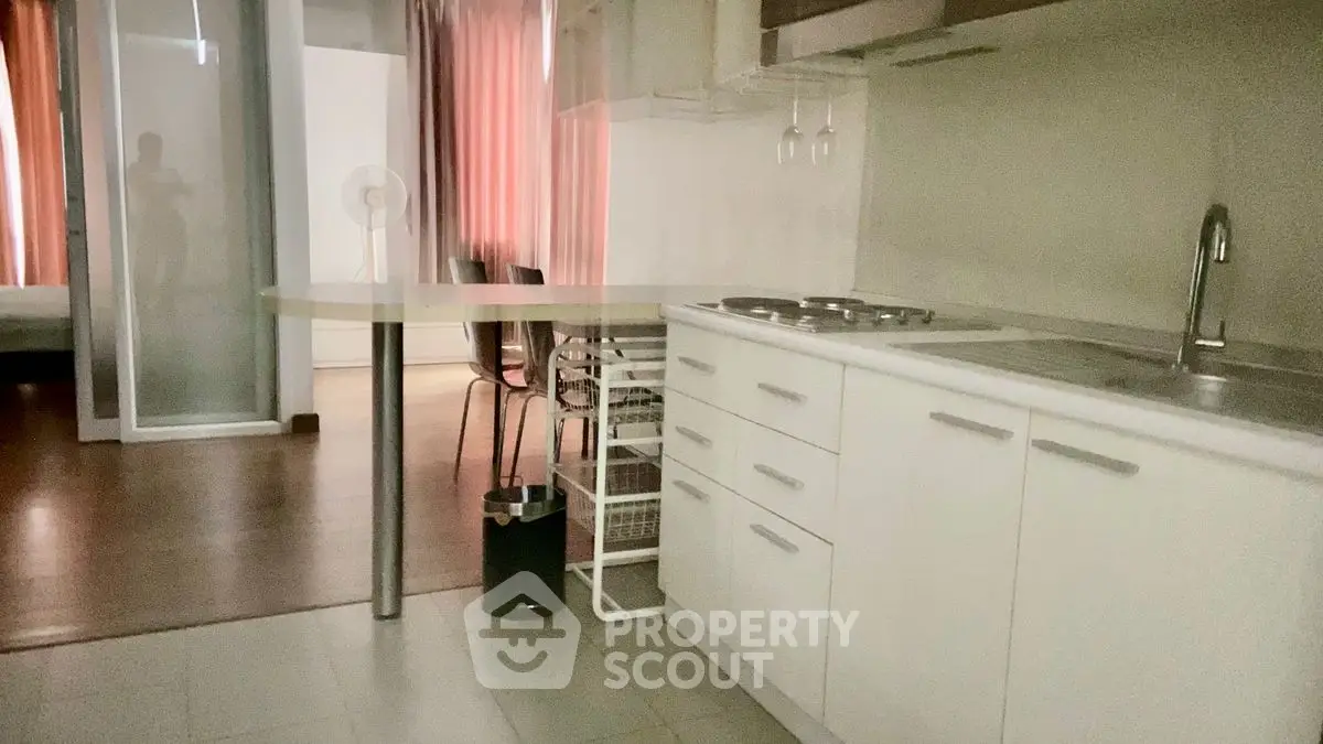 Modern kitchen with sleek white cabinets and open layout, adjacent to dining area with natural light.
