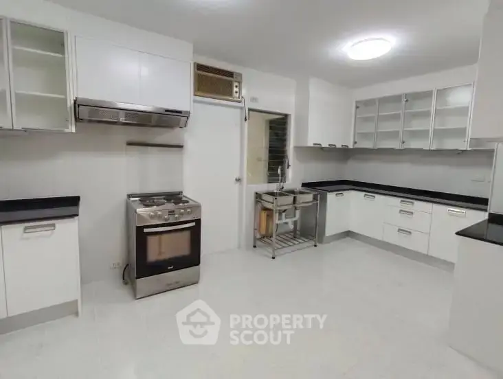 Spacious modern kitchen with sleek white cabinets and stainless steel appliances.